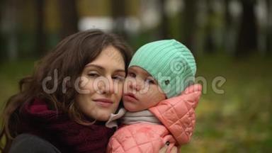 秋天公园里有个孩子的美丽年轻女人的肖像。 两个，年轻母女的肖像。 慢慢慢慢